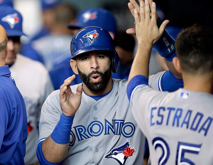 Toronto Blue Jays Jose Bautista is congratulated by teammate Marco Estrada after scoring on a Russell Martin two-run triple against the Houston Astros in the first inning of a baseball game Saturday, May 16, 2015, in Houston.