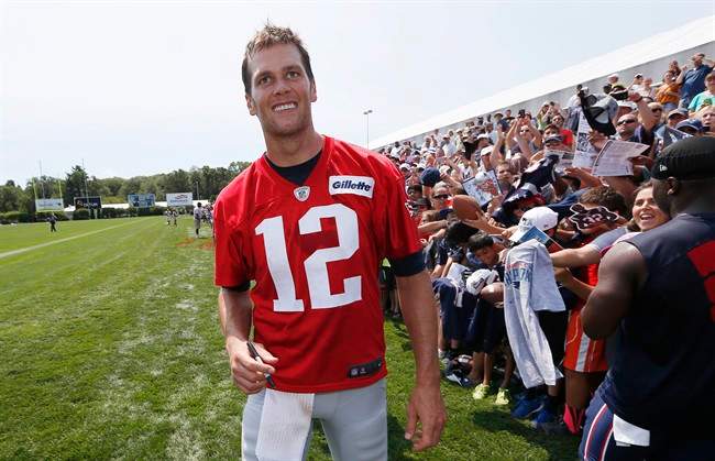 New England Patriots quarterback Tom Brady walks down the line of fans signing autographs during an NFL football training camp in Foxborough, Mass., Saturday, Aug. 1, 2015. 