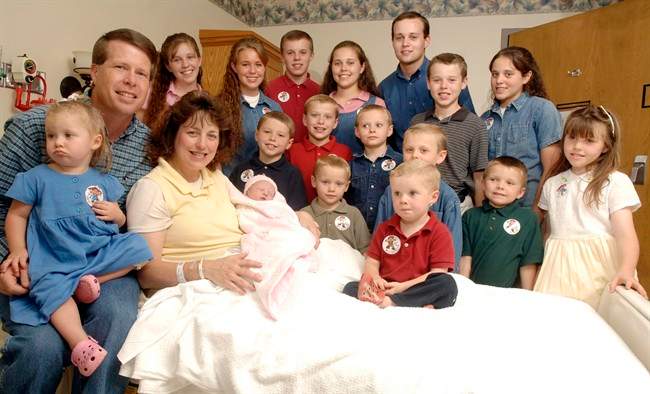 In this Aug. 2, 2007 file photo, Michelle Duggar, left, poses with her husband Jim Bob, second from left, and children, including their oldest son Josh, tallest standing, after the birth of her 17th child in Rogers, Ark.