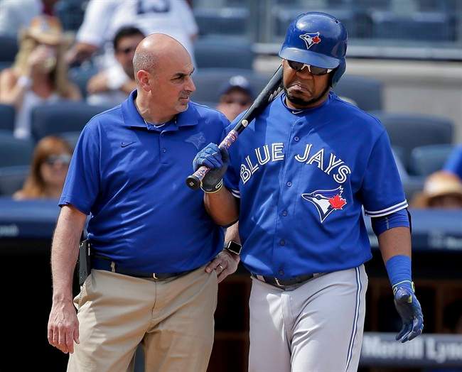 Toronto Blue Jays' Edwin Encarnacion, right, shrugs off questions from a trainer during an at-bat against the New York Yankees during the eighth inning of a baseball game, Saturday, Aug. 8, 2015, in New York.