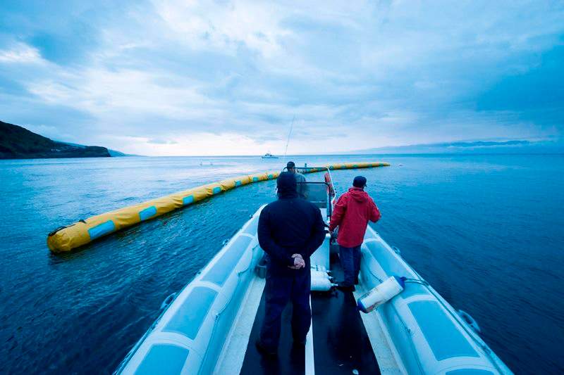 In this March 2014 photo, provided by The Ocean Cleanup shows crew members inspecting a 40-meter long proof-of-concept barrier in Pico Island, Azores, Portugal. 