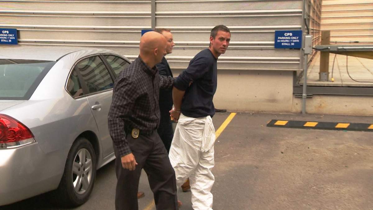 Calgary police officers escort a man into the Arrest Processing Unit following a death in the 400 block of Pinehill Road N.E. on Tuesday, August 25, 2015.