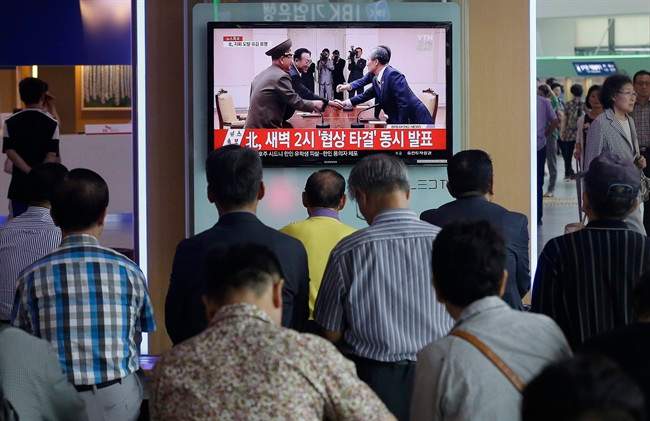 People watch a TV news program reporting South and North Korea reached an agreement, at the Seoul Railway Station, South Korea, Tuesday, Aug. 25, 2015.