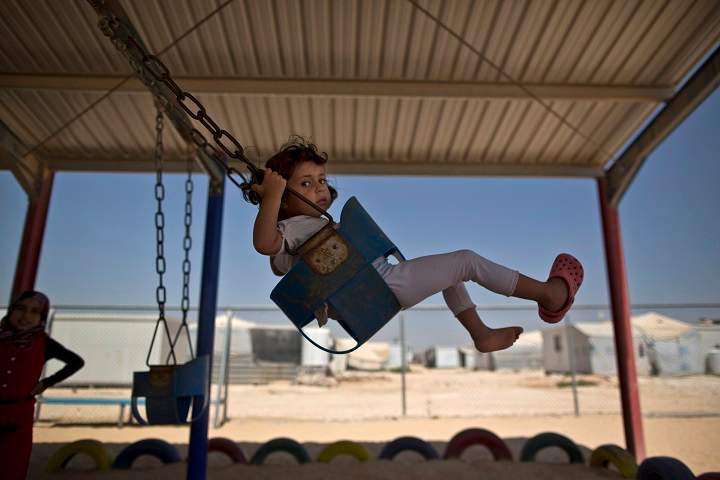 A Syrian girl plays on a swing while she and other children celebrate the first day of the Eid al-Fitr holiday that marks the end of the holy fasting month of Ramadan at Zaatari refugee camp, in Mafraq, Jordan, Friday, July 17, 2015. 