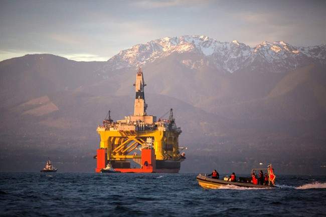 In this April 17, 2015 file photo, with the Olympic Mountains in the background, a small boat crosses in front of the Transocean Polar Pioneer, a semi-submersible drilling unit that Royal Dutch Shell leases from Transocean Ltd., as it arrives in Port Angeles, Wash., aboard a transport ship after traveling across the Pacific before its eventual Arctic destination. 