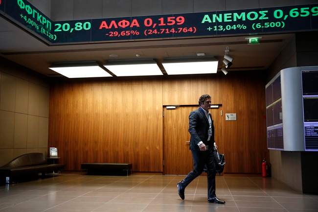 A man walks at the reception hall of the Athens' Stock Exchange as stock prices are on display on a ticker screen in Athens, Greece, on Tuesday, Aug. 4, 2015.