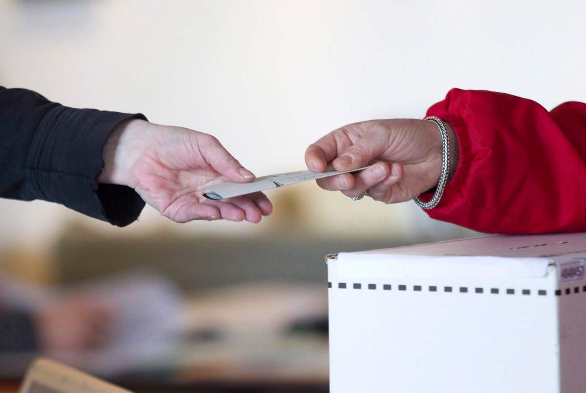 An election official hands back to a voter her marked ballot to place in the ballot box so she can cast her vote for the federal election at a polling station on Toronto's Ward Island   on Monday May 2, 2011. 