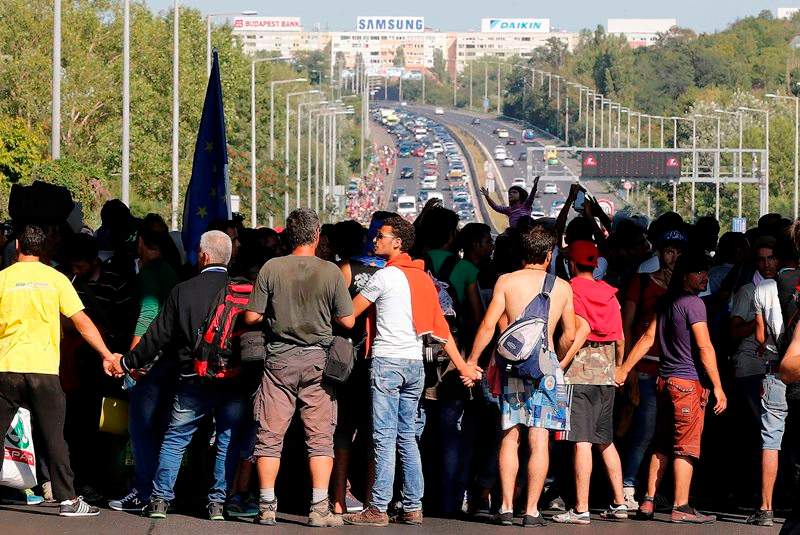 Migrants hold hands as they walk out of Budapest, Hungary, on Friday. AP Photo/Frank Augstein