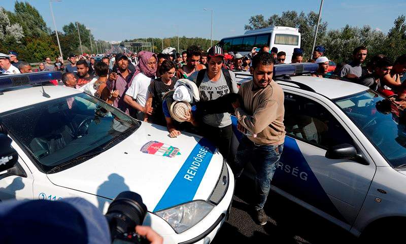 Migrants thread their way through a police blockade as they walk out of Budapest, Hungary, Friday, Sept. 4, 2015. Over 150,000 people seeking to enter Europe have reached Hungary this year, most coming through the southern border with Serbia, and many apply for asylum but quickly try to leave for richer EU countries.