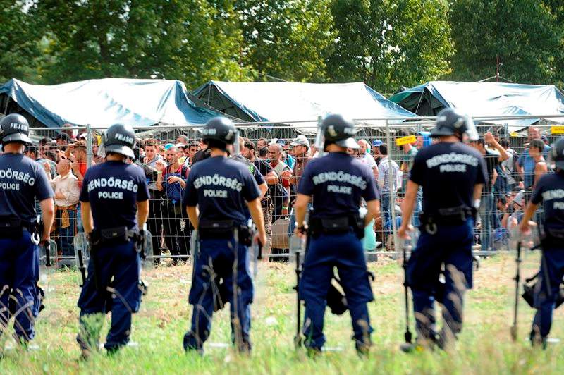 Migrants and Hungarian police officers confront at the reception center, in Roszke, southeast from Budapest, Hungary, Friday, Sept. 4, 2015. About three hundred people broke out of the reception center near the southern border between Hungary and Serbia earlier on Friday.