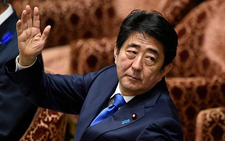 Japanese Prime Minister Shinzo Abe raising his hand before answering a question from a lawmaker during a committee session debating the security bills at the parliament in Tokyo, Japan. 