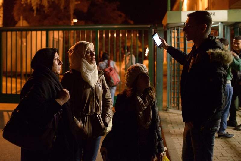 In this Sept. 16, 2015 photo Raghad, center, and Reem Habashieh, second from left, and their mother Khawla Kareem, left, get information by a Syrian man as they arrive at an asylum seeker center in Chemnitz, eastern Germany. 