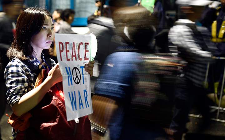 A young woman holds a placard protesting against controversial military reform bills outside Japan's parliament in Tokyo, Japan, 18 September 2015.