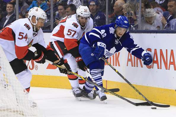 Toronto Maple Leafs' forward Brendan Leipsic fights for the puck along the boards behind the net with Ottawa Senators Nick Tuzzolino (57 and Guillame Lepine (54) during NHL Pre-season hockey action at the Air Canada Centre in Toronto on  September 21, 2015. (Cole Burston/Toronto Star via Getty Images).