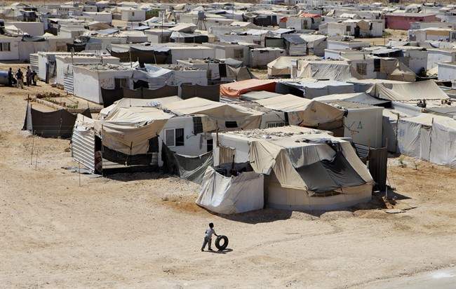 FILE- In this Wednesday, July 29, 2015 photo, a Syrian refugee boy plays with a tire at Zaatari refugee camp, in Mafraq, Jordan. The United Arab Emirates on Wednesday, Sept. 9, 2015 defended its response to the Syrian refugee crisis in the face of criticism that the country and other oil-rich Gulf states should be doing more to address the issue. (AP Photo/Raad Adayleh, File).