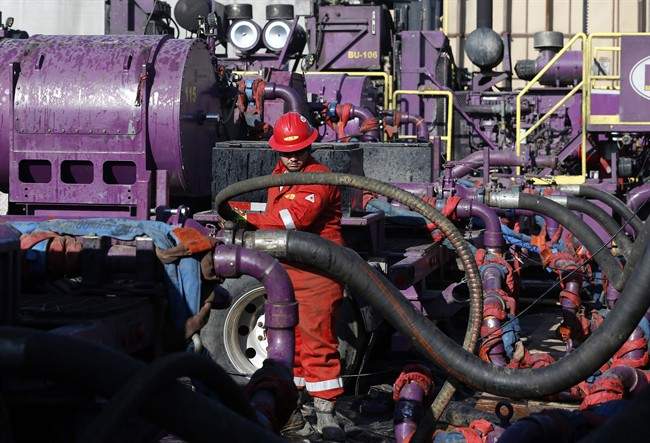 FILE - In this March 25, 2014 file photo, a worker adjusts hoses during a hydraulic fracturing operation at a gas well, near Mead, Colorado.  