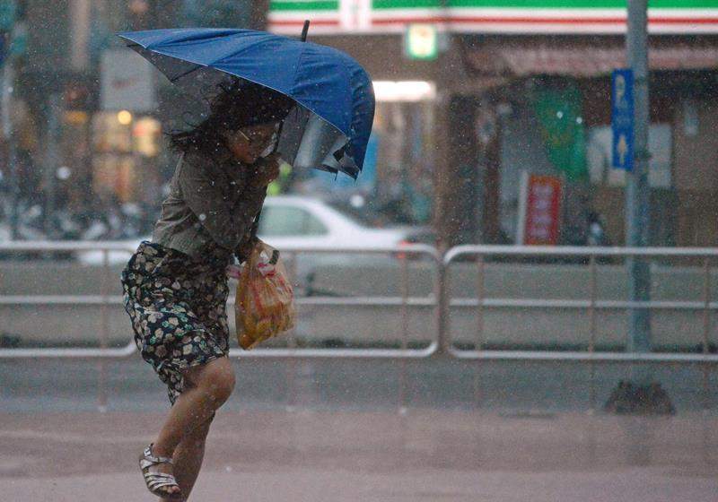 A woman uses an umbrella against strong wind and rain brought by typhoon Dujuan at Tamshui district, New Taipei City on September 28, 2015.