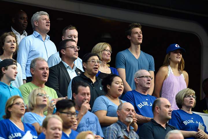 Conservative Leader Stephen Harper and his family sing the national anthem as the Toronto Blue Jays prepare to take on the Cleveland Indians during American League baseball action in Toronto on Monday, August 31, 2015. 