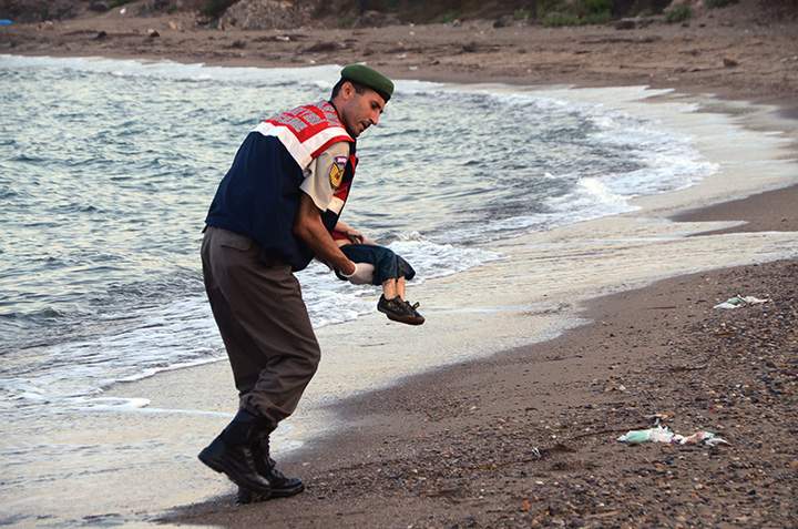 A paramilitary police officer carries the lifeless body of a migrant child after a number of migrants died and a smaller number were reported missing after boats carrying them to the Greek island of Kos capsized, near the Turkish resort of Bodrum early Wednesday, Sept. 2, 2015.