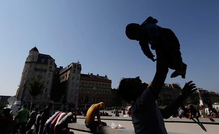 A migrant holds up a baby in front of the Keleti Railway Station in Budapest, Hungary, Wednesday, Sept. 2, 2015, as hundreds demanded to be let on trains to Germany.
