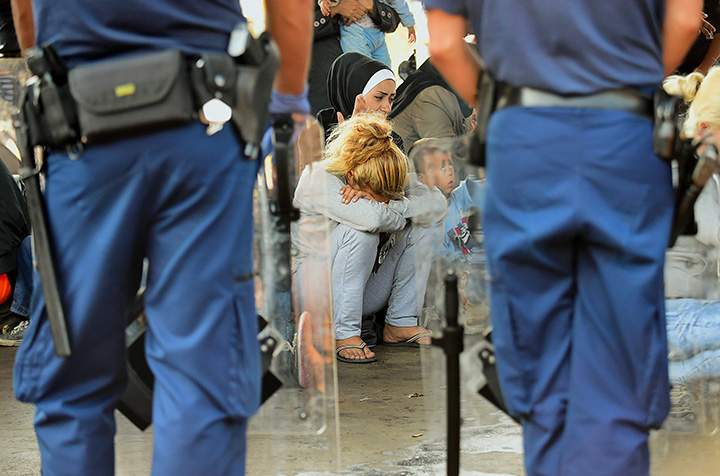 Hungarian police officers face a group of Syrian migrants on the platform of the Kobanya-Kispest station, Budapest suburb, on September 2, 2015, as the refugees refused to board a train to the Debrecen camp.