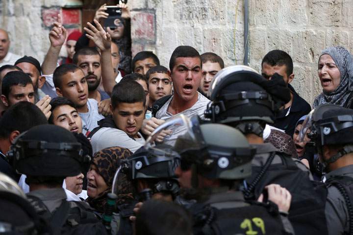 Palestinians shout in front of Israeli security forces who block a road leading to the Al-Aqsa mosque compound in Jerusalem's Old City on September 13, 2015.