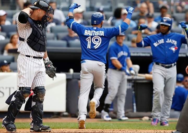 New York Yankees catcher Brian McCann, left, reacts as Toronto Blue Jays Jose Bautista (19) celebrates heading to the dugout after hitting an eighth-inning, solo, home run as on-deck-batter Edwin Encarnacion right, joins the celebration during the first baseball game of a doubleheader at Yankee Stadium in New York, Saturday, Sept. 12, 2015. 