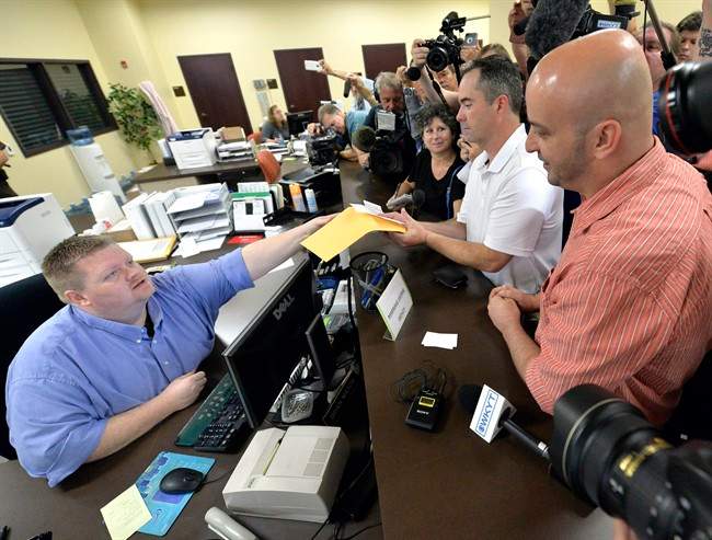 Rowan County deputy clerk Brian Mason, left, hands James Yates, and his partner William Smith Jr., their marriage license at the Rowan County Judicial Center in Morehead, Ky., Friday, Sept. 4, 2015.