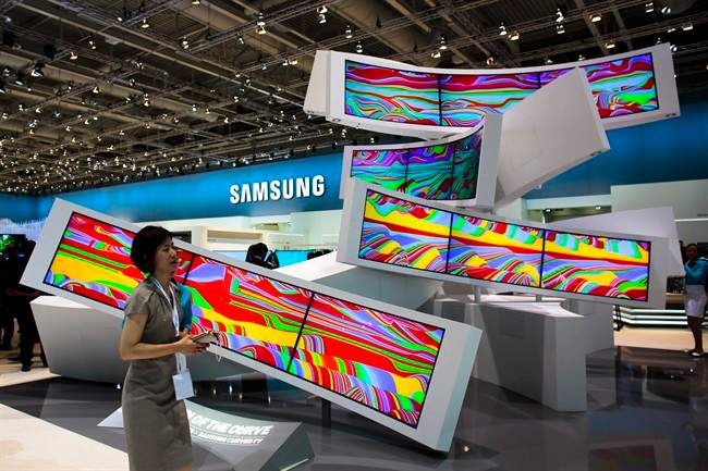 This is a Friday, Sept. 5, 2014 file photo of a woman as she passes an installation with curved screens, displayed by Samsung at the consumer electronic fair IFA in Berlin, Germany. Europe’s flagship gadget show, the IFA in Berlin, opens its doors to the public on Friday Sept. 4, 2015 . Almost 1,500 companies and over 250 000 people are expected to visit the event, which runs through Sept. 9.