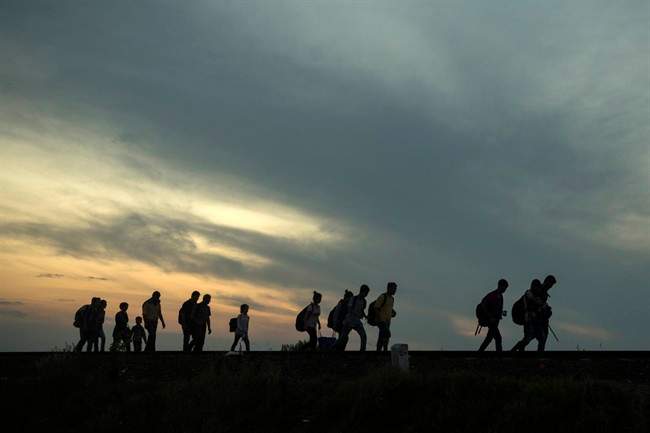 This is a Thursday Sept. 3, 2015 file photo of a group of refugees as they walk along the railway tracks near the town of Roszke, Hungary, after crossing the border from Serbia.