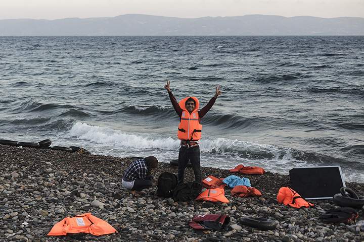 A Syrian refugee flashes the victory sign after arriving on the shores of Lesbos Island in Greece in an inflatable boat from Turkey on August 23, 2015.