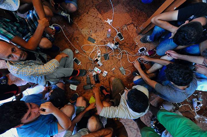 Migrants charge their mobile phones at the Eastern (Keleti) railway station in Budapest on August 31, 2015.