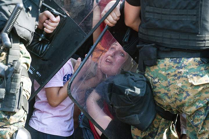 A woman looks up at police blocking a group of migrants trying to cross the Macedonian-Greek border near the town of Gevgelija on August 21, 2015. 