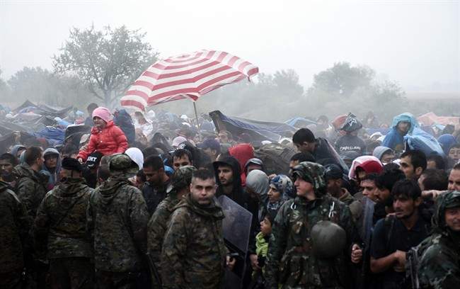 Refugees and migrants wait to pass from the northern Greek village of Idomeni to southern Macedonia, Thursday, Sept. 10, 2015.