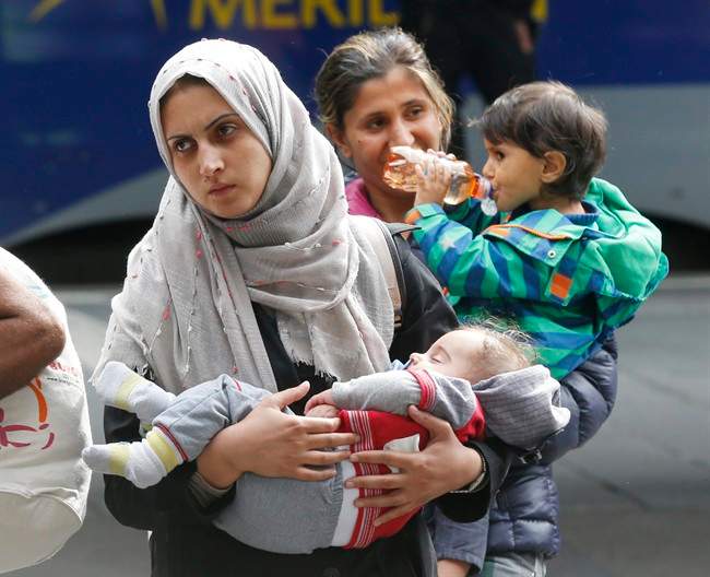 A woman carries her child as they arrive at the main train station in Munich, Germany, Saturday, Sept. 5, 2015.
