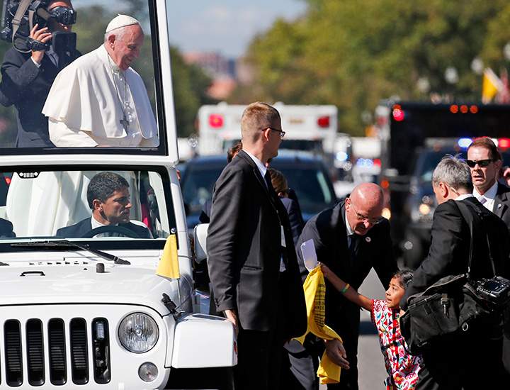 Sophie Cruz, 5, of suburban Los Angeles reaches to give Pope Francis a letter and t-shirt during a parade in Washington, Wednesday, Sept. 23, 2015.