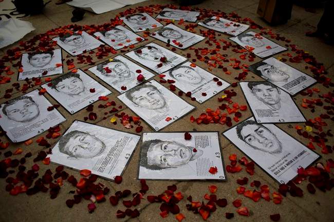 In this March 26, 2015 file photo drawings of some of 43 missing students are surrounded by flower petals, forming the shape of a heart, during a protest marking the six-month anniversary of their disappearance, in Mexico City.