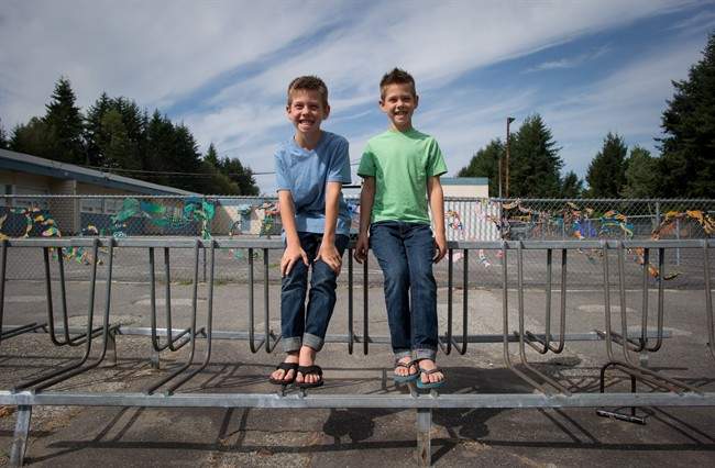 Twin eight-year-old brothers Riley, left, and Taylor Dalby sit for a photograph outside South Park School where they will enter Grade 3 this year, in Delta, B.C., on Monday August 24, 2015. 