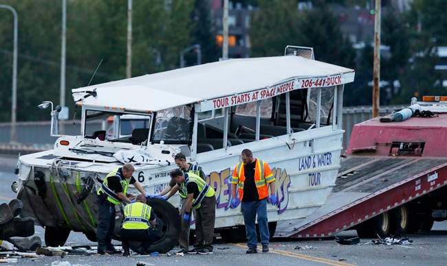 Seattle Police officers photograph the front tire and wheel of a "Ride the Ducks" tourist vehicle before the bus is loaded onto a flatbed tow truck Thursday, Sept. 24, 2015, after it was involved in a fatal crash with a charter passenger bus earlier in the day in Seattle.
