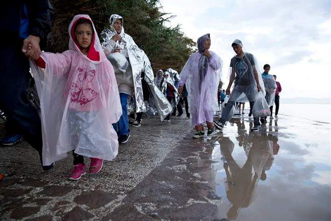 Afghan migrants walk on a street in the rain, after they arrived with from Turkey to the shores of the Greek island of Lesbos, Thursday, Sept. 24, 2015. More than 260,000 asylum-seekers have arrived in Greece so far this year, most reaching the country's eastern islands on flimsy rafts or boats from the nearby Turkish coast.(AP Photo/Petros Giannakouris).