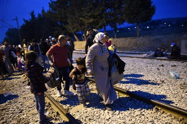 Refugees and migrants walk on the railway tracks as they wait to pass from the northern Greek village of Idomeni to southern Macedonia, Sunday, Sept. 20, 2015. More than 2,000 people wait at the small village of about 100 inhabitants every day to be let into Macedonia, from where they continue through Serbia and Hungary to seek asylum in wealthier European countries.