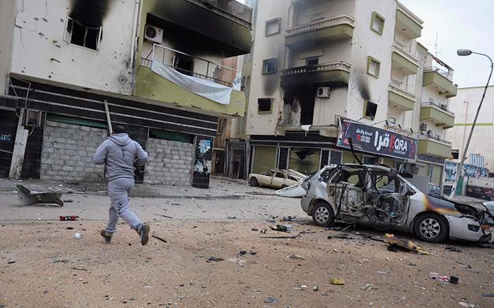 A man runs between buildings damaged during clashes between Libyan military soldiers and Islamic extremist militias in Benghazi, Libya, Thursday, Oct. 30, 2014.