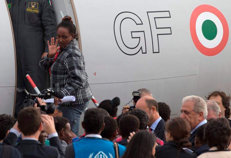 An Eritrean refugee waves as she boards an Italian Financial police aircraft which will take her and other 18 refugees to Sweden, at Rome's Ciampino airport, Friday, Oct. 9, 2015. 