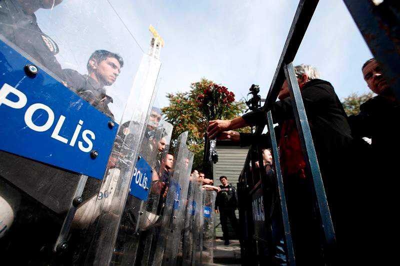 A protester offers carnations to Turkish police blocking the way to the site of Saturday’s explosions in Ankara, Turkey, Sunday, Oct. 11, 2015.