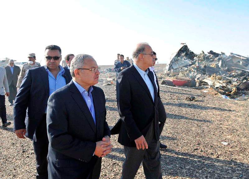 In this image released by the Prime Minister’s office, Sherif Ismail, center, visits the site where a plane crashed in Hassana Egypt, Friday, Oct. 31, 2015