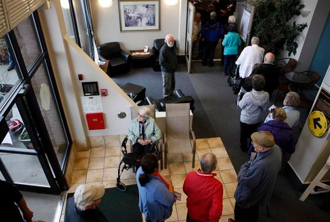 Voters form a line as they wait to cast their ballots in Sidney, B.C., Monday, Oct. 19, 2015.