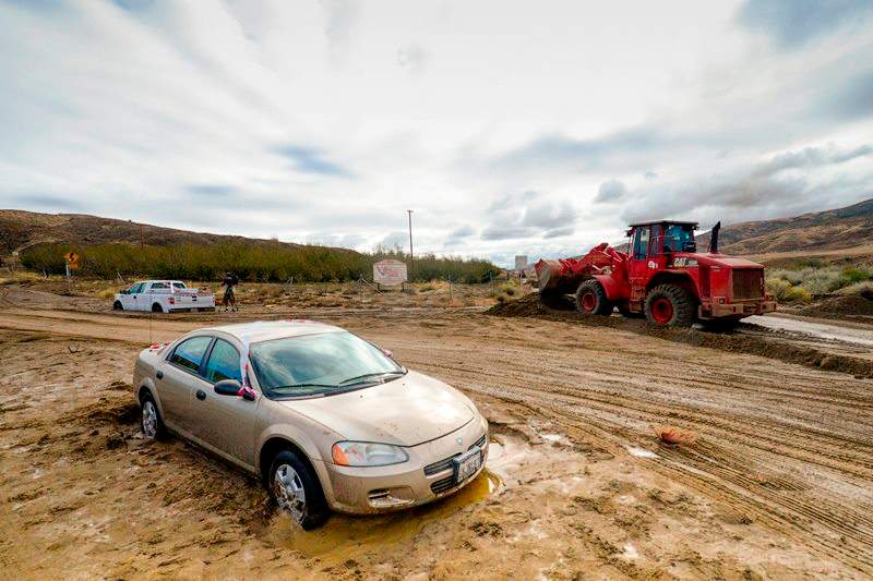 A Los Angeles County firefighter use a front end loader to clear mud on Friday, Oct. 16, 2015, after a flash floods the day before sent mud and debris through Elizabeth Lake road in Leona Valley, Calif., trapping cars and closing roads.