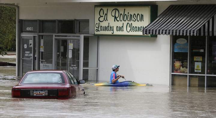 Jordan Bennett, of Rock Hill, S.C., paddles up to a flooded store in Columbia, S.C., Sunday, Oct. 4, 2015.