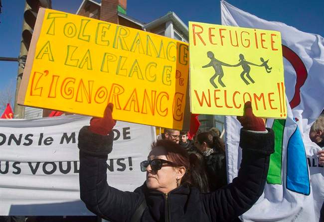 A woman holds up signs during a demonstration to denounce the anti-Islam group PEGIDA in Montreal on March 28, 2015.