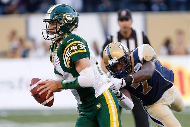 Edmonton Eskimos' quarterback Mike Reilly (13) gets away from Winnipeg Blue Bombers' Demond Washington (7) during the second half of CFL action in Winnipeg Saturday, October 3, 2015.